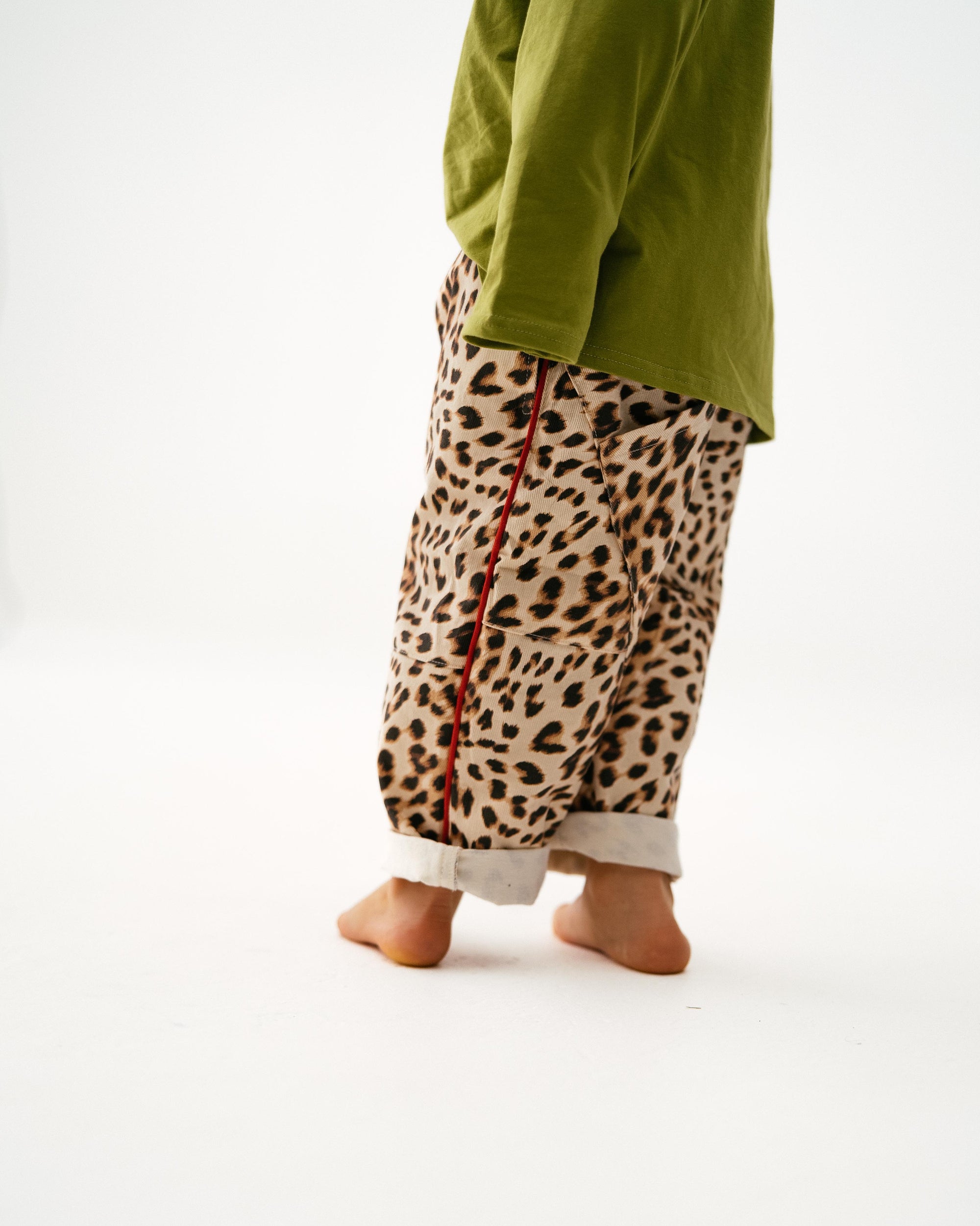 Person wearing leopard print pants and a green top on a white background