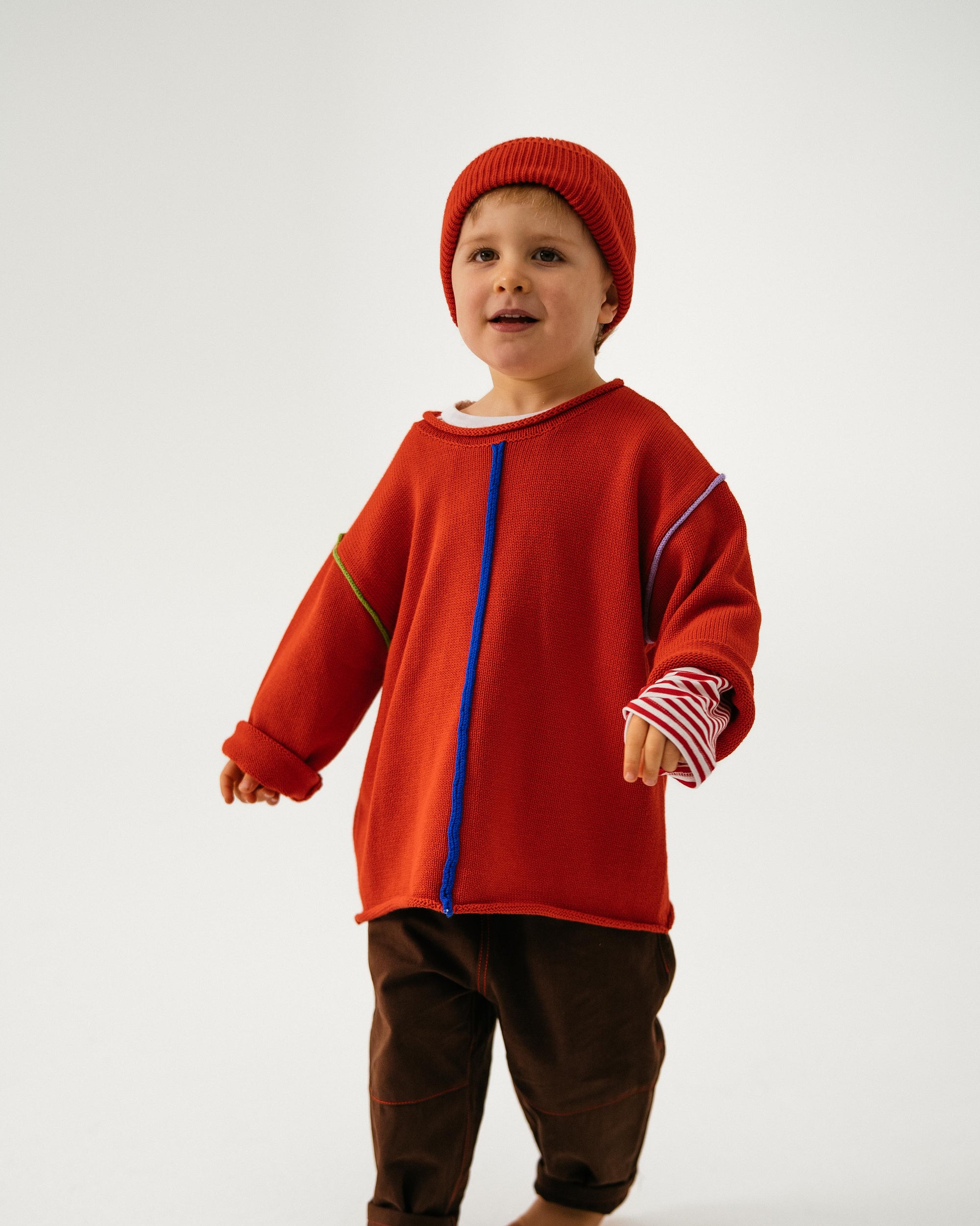 Child wearing a red outfit with a blue zipper on a white background